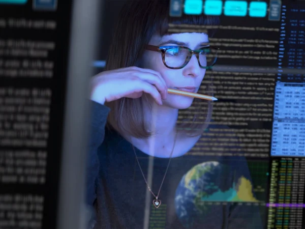 Woman in deep thought holding pencil looking at a computer screen, University of Connecticut Non-Credit Programs